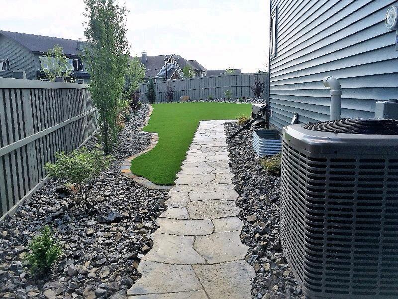Side yard with irregular flagstone pathway through turf and gravel